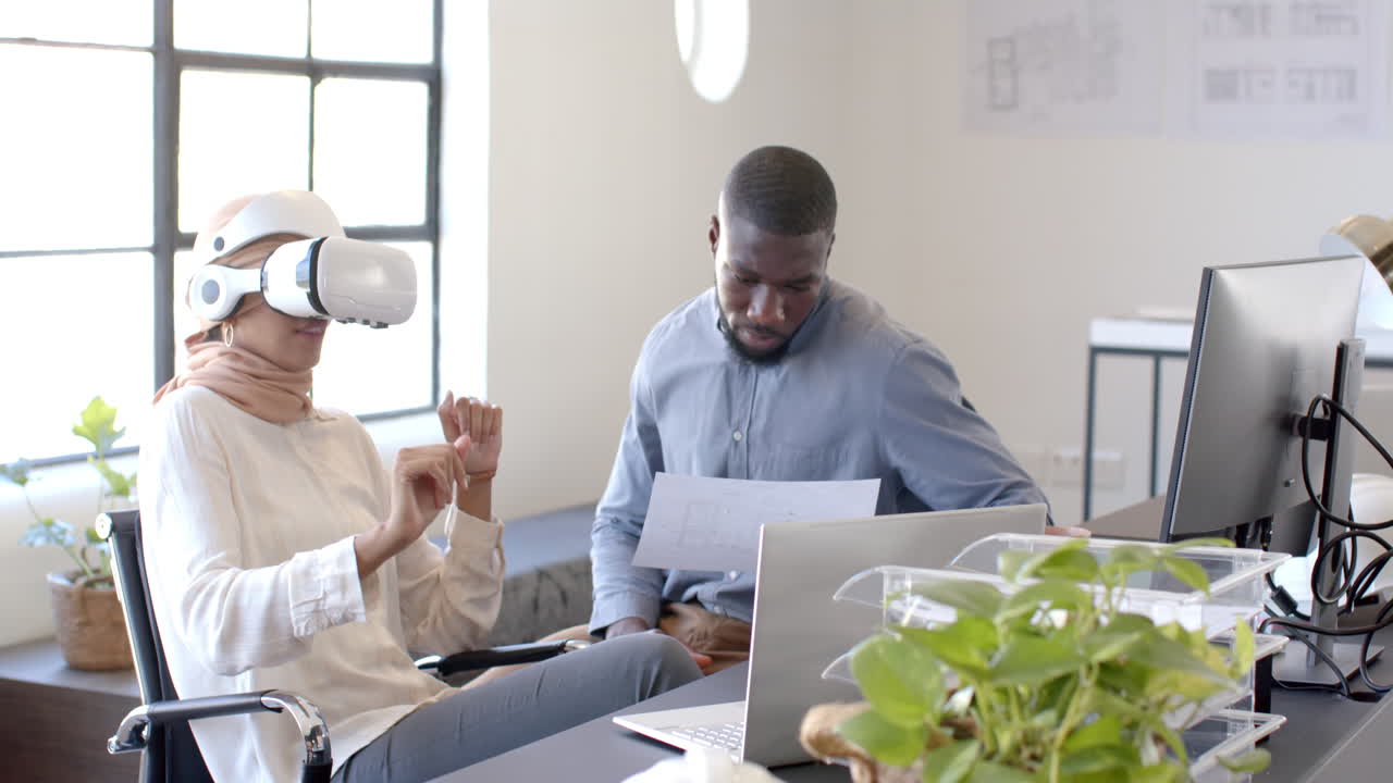 Using VR headset, woman interacting while man reviewing documents in office