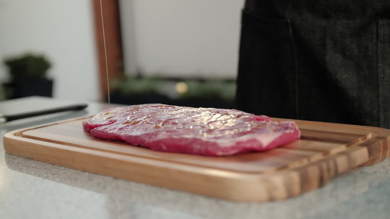 Chef che irrora olio d'oliva su una bistecca di manzo, al rallentatore