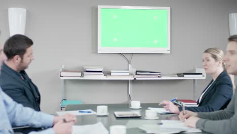 los colegas tienen una discusión en la sala de reuniones frente a una pantalla verde