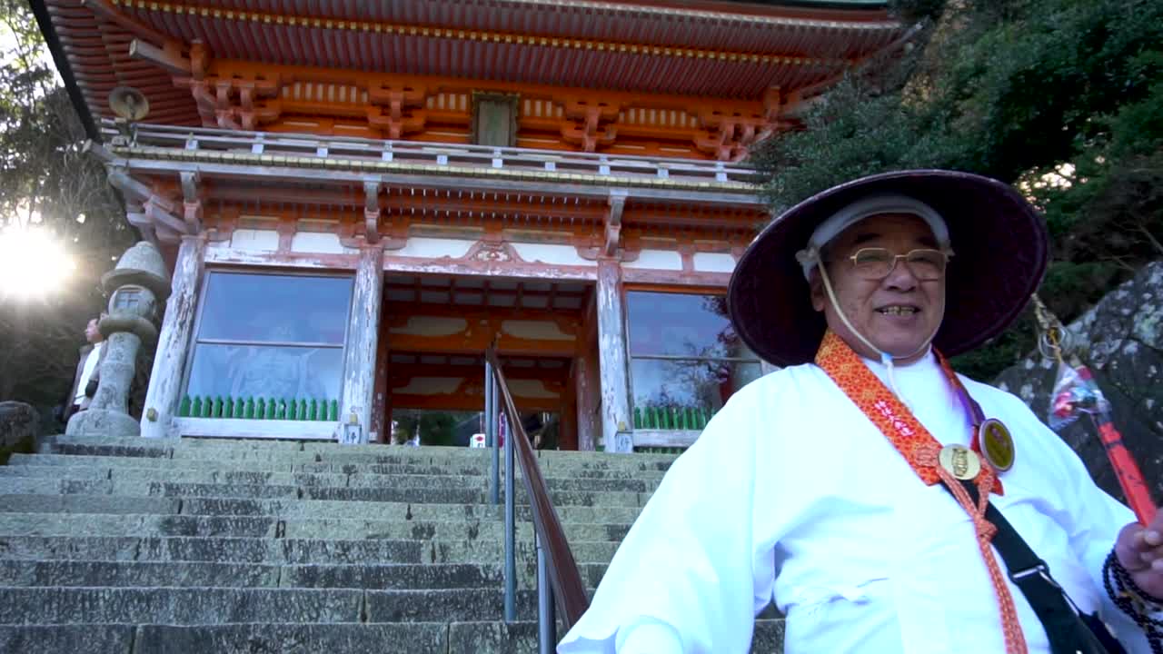 anciano japonés vestido con ropa tradicional bajando las escaleras en el santuario de nachi en wakayama, japón