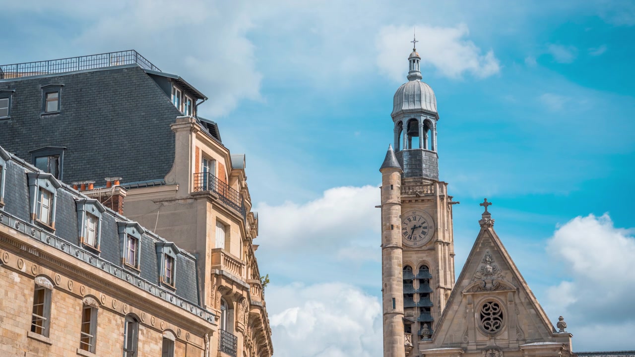 Klokketårn i sten fra Saint-Étienne-du-Mont rejser sig over klassiske parisiske hustage mod en lys, skyfyldt himmel