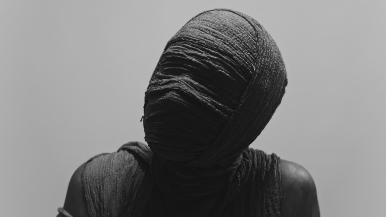 A mummy of a woman on a white backdrop turns her head