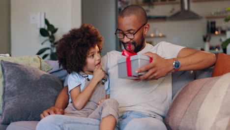 father and child exchanging a gift on the couch