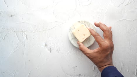 hand holding a piece of soap on a marble coaster