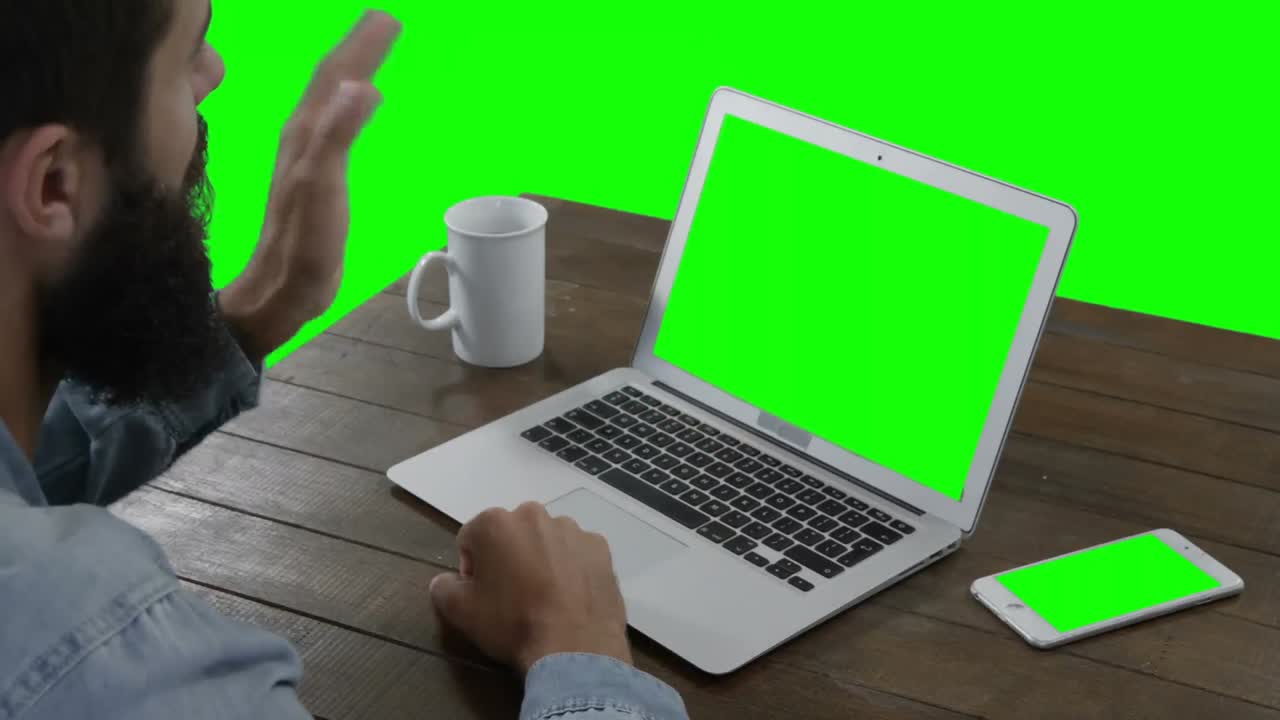 hombre sentado en la mesa haciendo una llamada de video en una computadora portátil