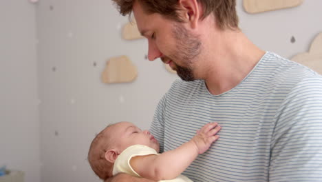 father cuddling sleeping baby son in nursery