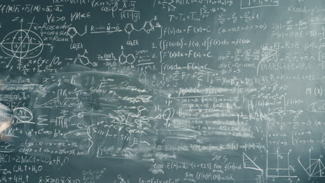 student working on a heavily-written chalkboard