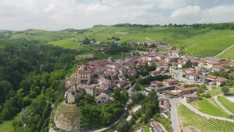 barolo castle in langhe wine region, cuneo, piedmont, italy. 4k aerial view of the village and the vineyards, flying forward to the town.