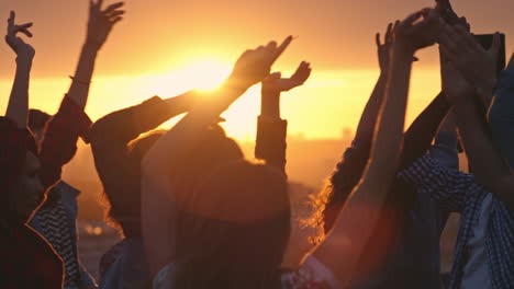 group of young multi ethnic people having fun dancing with raised arms to the music played by dj at rooftop party at sunset