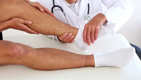 Doctor-checking-sportsmans-injured-ankle
