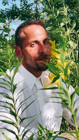 man in a white shirt in a garden with yellow flowers