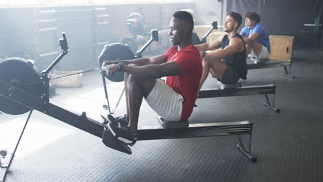group of diverse young men training on rowing machines in gym