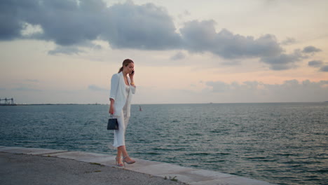 gorgeous woman calling coast beautiful evening. businesswoman walking talking