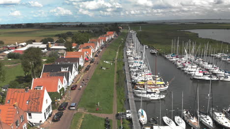 Inclinación-Aérea-Que-Muestra-La-Zona-Del-Puerto-Marítimo-Para-Embarcaciones-De-Recreo-Y-Veleros-Con-Casas-Típicas-Del-Pueblo-Holandés-De-Durgerdam-En-Durgerdammerdijk-Cerca-De-Amsterdam-Contra-Un-Cielo-Azul-Con-Nubes