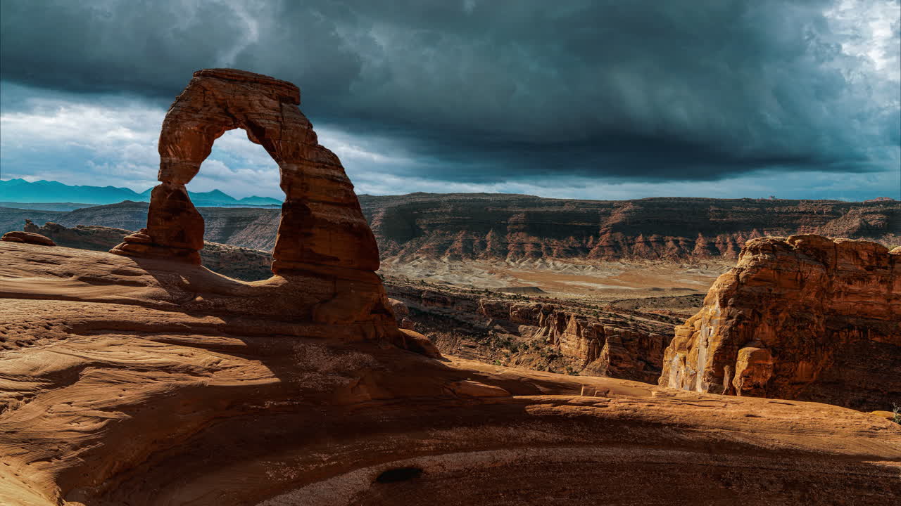 Selang waktu awan badai gelap yang menakjubkan dan sinematik di batu Delicate Arch yang terkenal di antara landmark pendakian Taman Nasional Arches di Utah, Arizona, Amerika Serikat