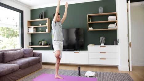 Hombre-Birracial-Enfocado-Practicando-Yoga-Parado-Sobre-Una-Pierna-En-La-Sala-De-Estar,-Espacio-Para-Copiar,-Cámara-Lenta