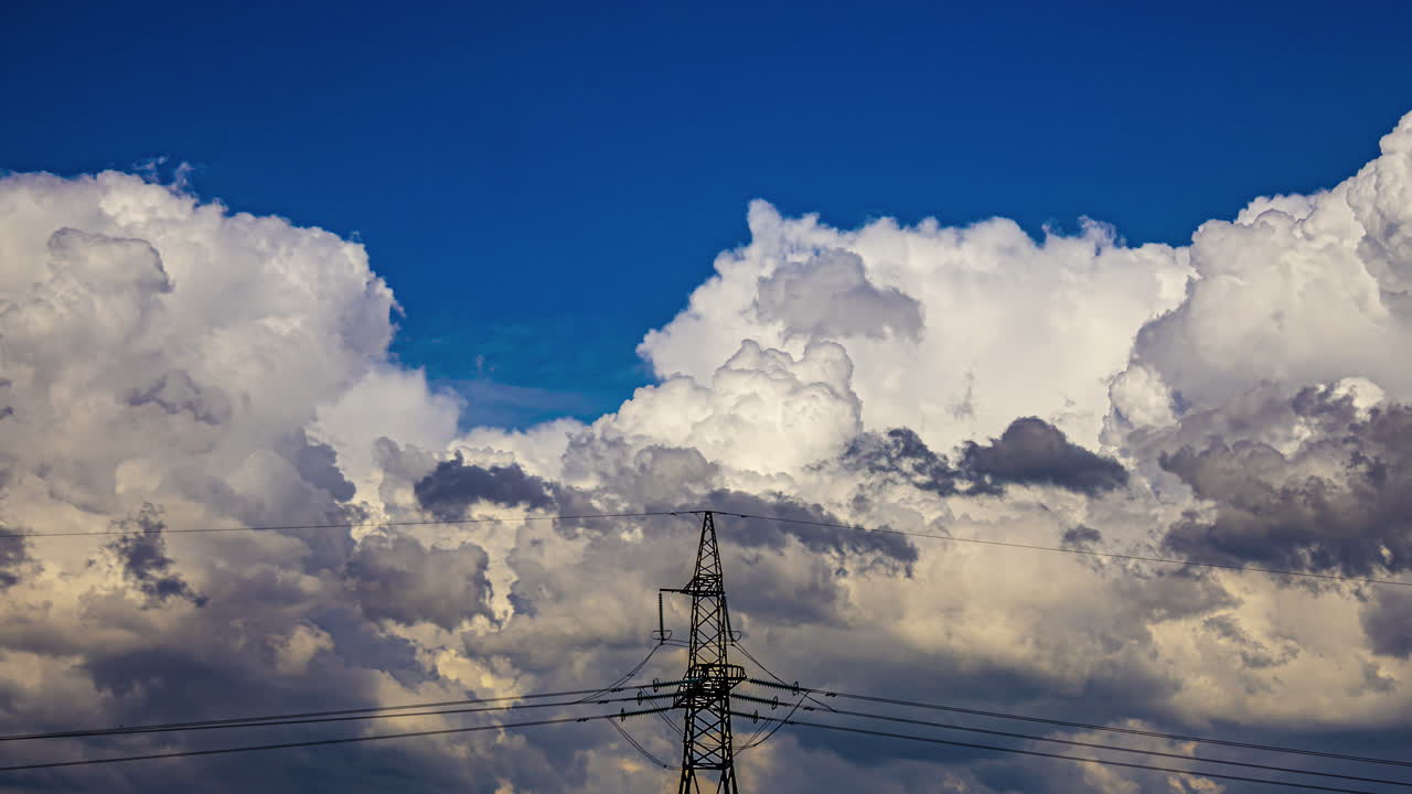 Cumulus Clouds and Electricity Pylon under a Blue Sky