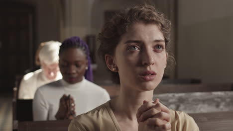 young female parishioner praying in catholic church