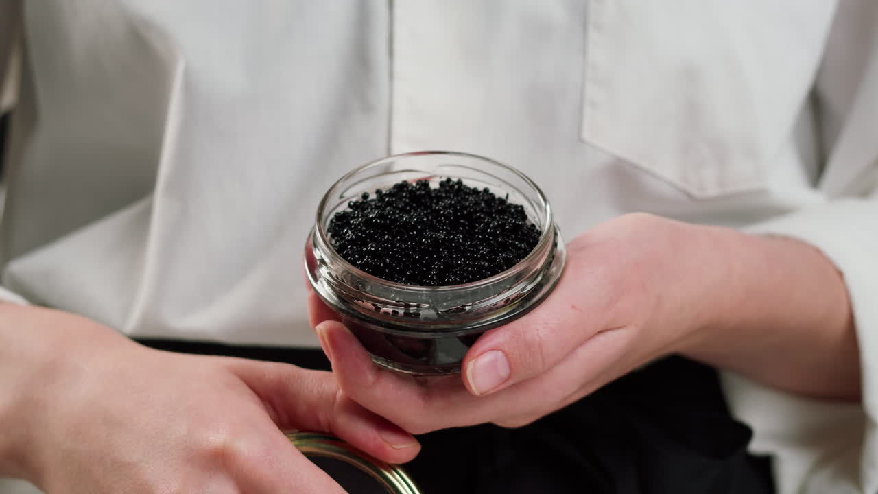 Mani che Aprono un Vasetto di Caviale Nero