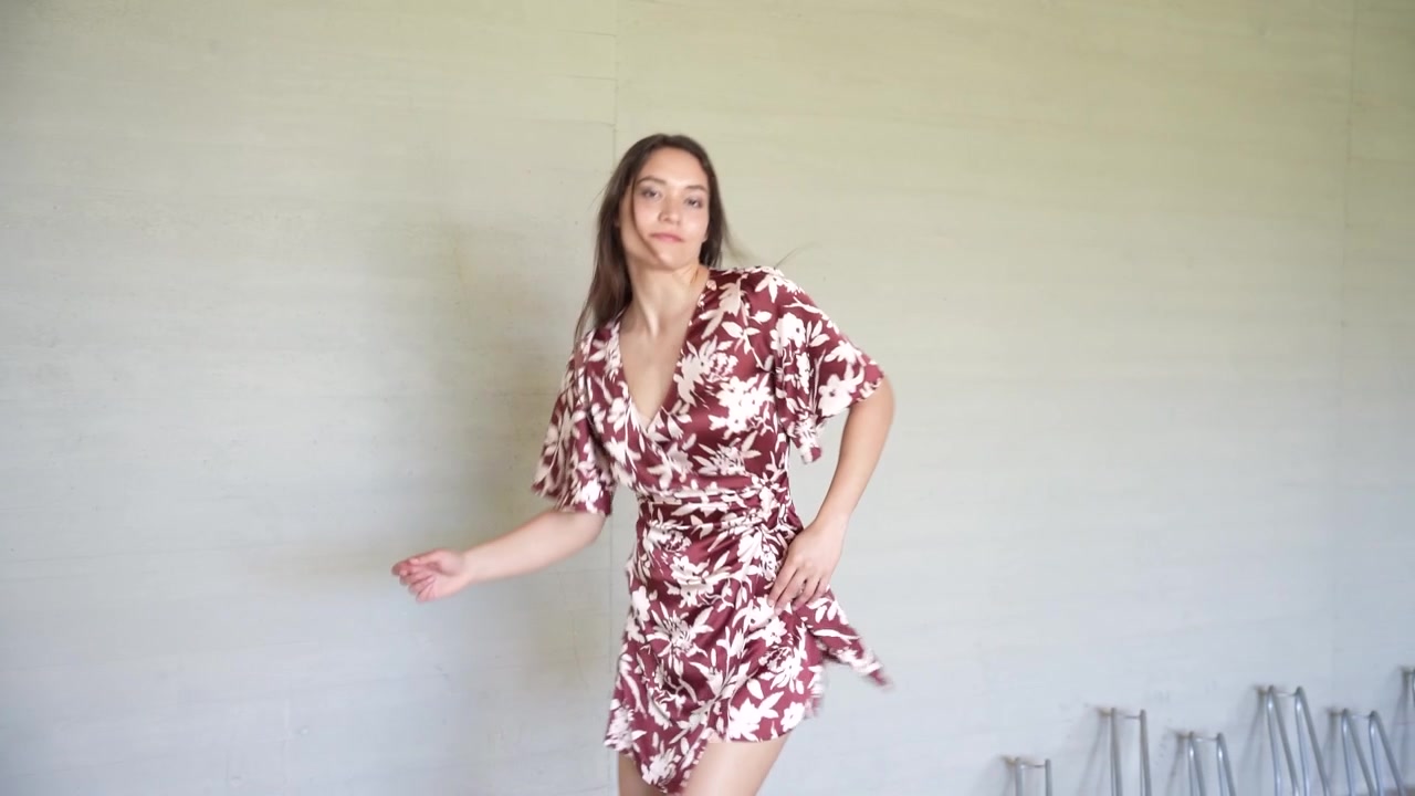 Una donna in un bellissimo abito floreale posa elegantemente su uno sfondo neutro.