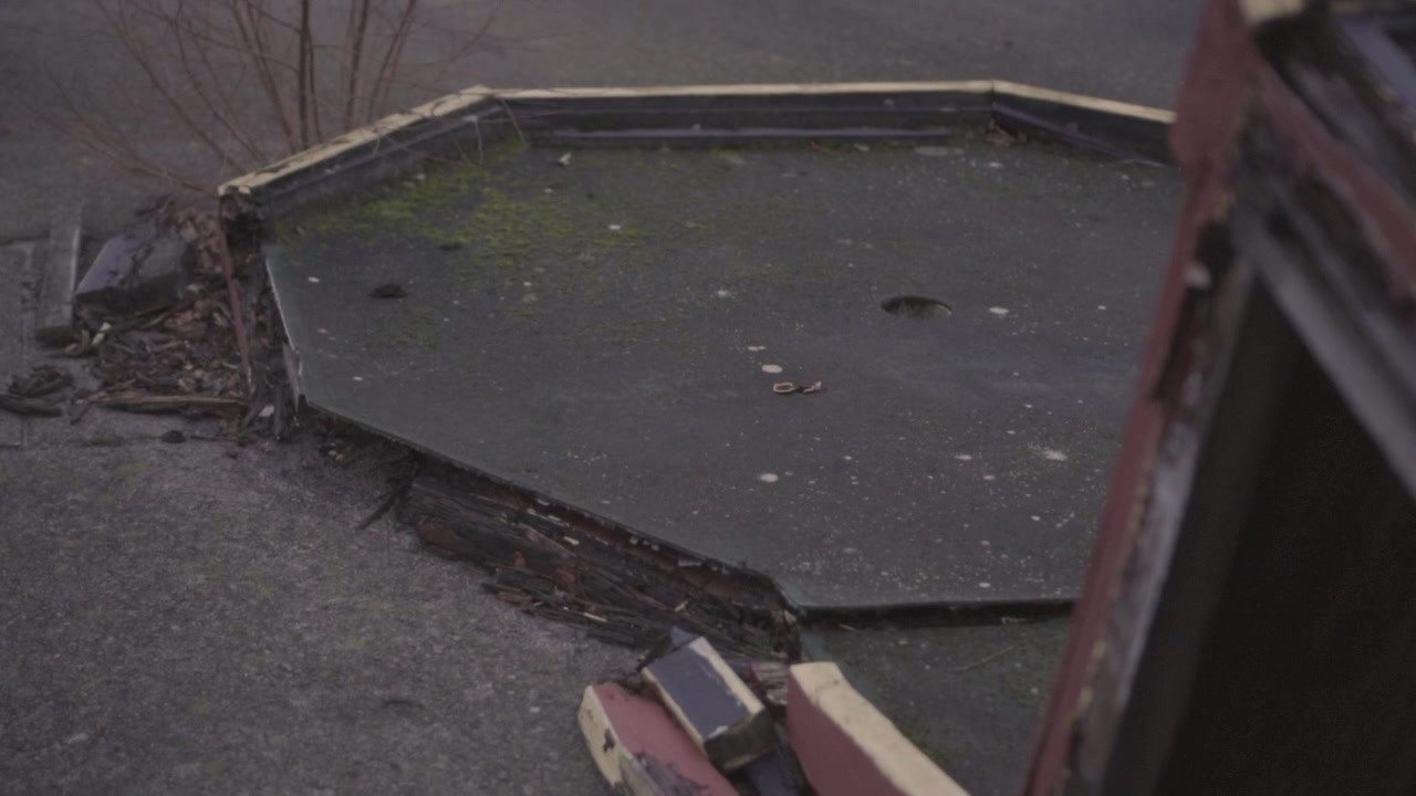 A worn-out mini golf course at an abandoned site, featuring broken obstacles, cracked surfaces and signs of long-term neglect.