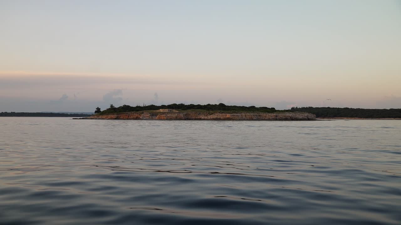 저녁이 그림 같은 해안선 위로 내려오면서 바다 물이 물결처럼 지나갑니다.