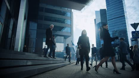 office managers and business people commute to work in the morning or from office on a sunny day on foot. pedestrians are dressed smartly. two businessmen shake hands. day in downtown.