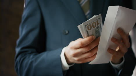 hands putting dollars envelope close up. man holding banknotes american currency