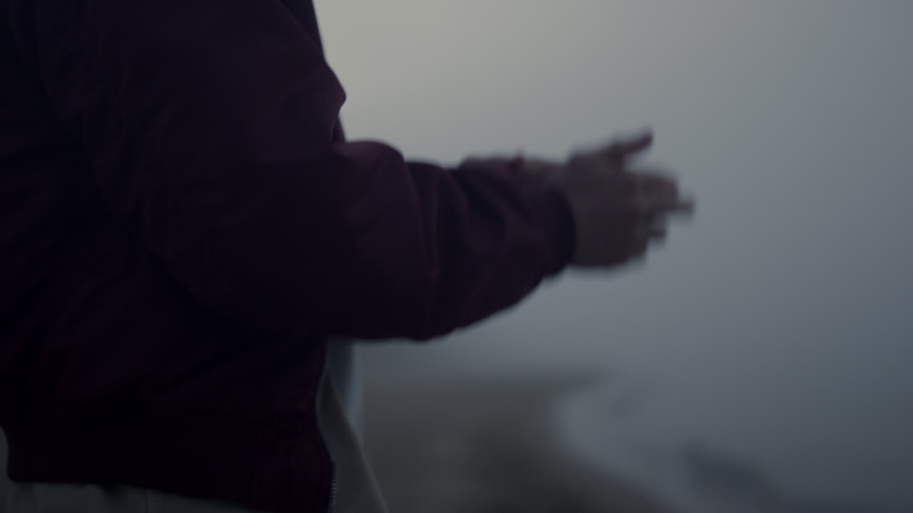 인식할 수 없는 남자가 바다 해변에서 춤을 추고 있다. 활동적인 남자가 손을 움직이고 있다.