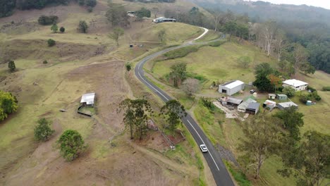 conducción de automóviles en una carretera asfaltada en una colina verde en el campo rural