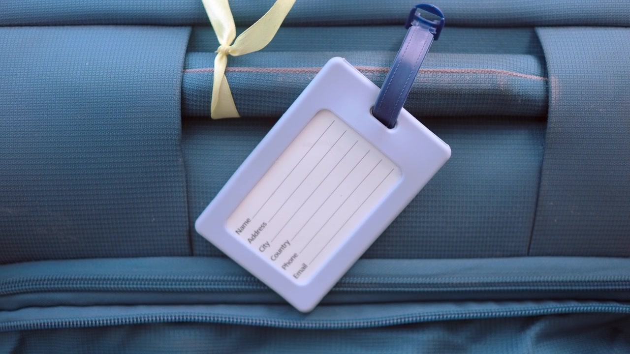 Etichetta per bagaglio vuota su una valigia blu pronta per il viaggio