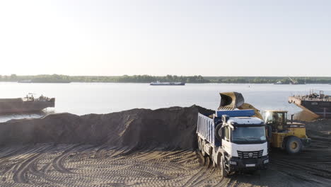 loading truck at river port with excavator