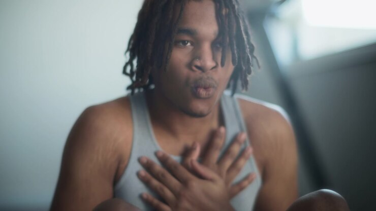 Athletic young man with dreadlocks doing sit-ups at home