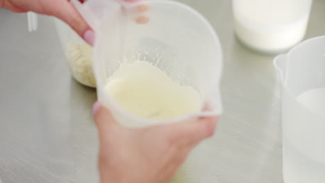 making cheese: pouring curd into a measuring cup