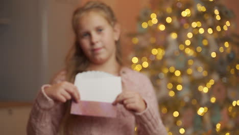 girl holding white christmas card with blank space showing it to camera