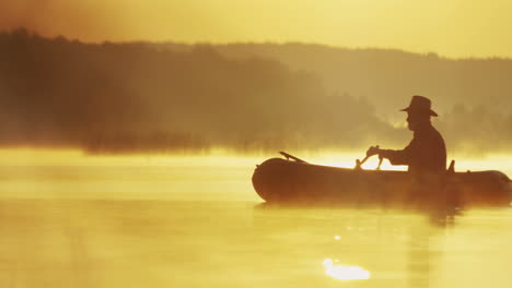 Fernsicht-Auf-Einen-älteren-Mann-Mit-Hut,-Der-Bei-Sonnenuntergang-In-Einem-Boot-Auf-Dem-See-Segelt