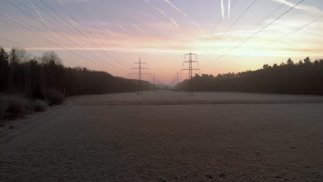 flying backwards removing from power lines in sunrise back light, public infrastructure for electricity distribution across countryside environment
