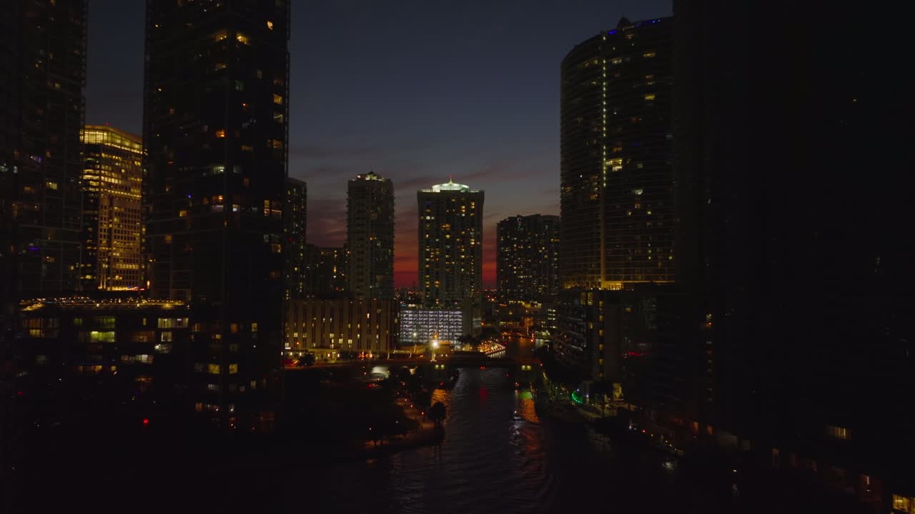 Amazing footage of night city. Tall apartment or office buildings along river against colourful sky after sunset. Miami, USA