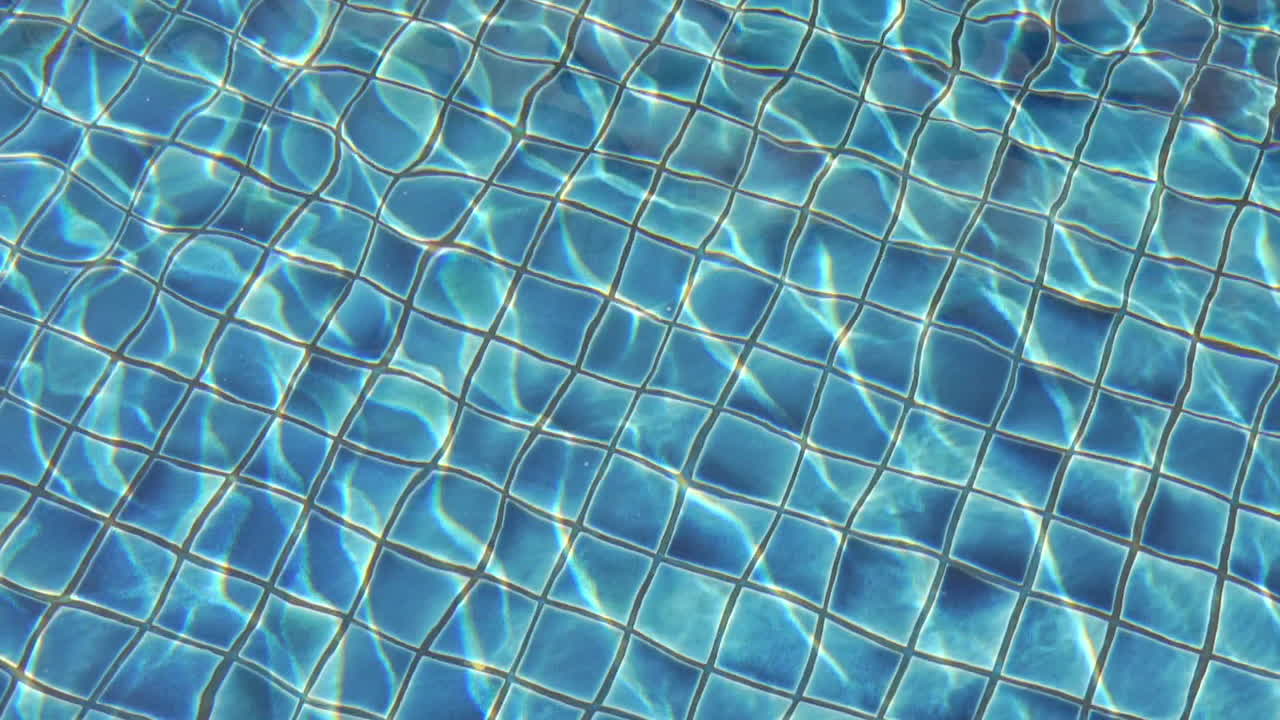 Top view shot blue tiled swimming pool background, refraction of sunlight in water slow motion