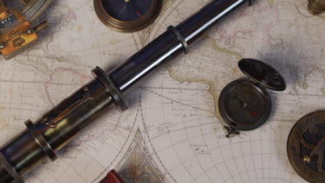 an antique brass telescope with sundial and compass with vintage map of the world for plotting adventure on a table