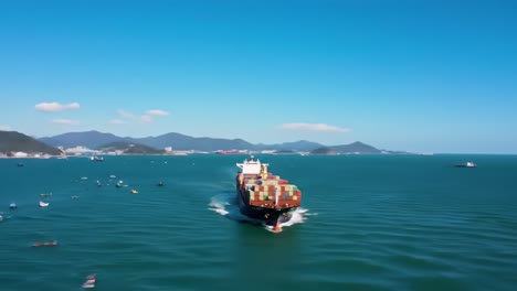 aerial view of a container ship navigating through calm waters, surrounded by small boats and scenic coastal landscapes under clear blue skies