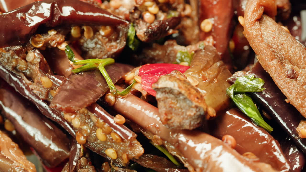 Close-up of fermented eggplants with red sweet pepper and mustard on plate. Preservation of vegetables in glass jars. Fermentation preserved aubergine with hot chilli peppers and greens.
