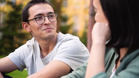 joven japonés hablando con su amiga mientras se sientan juntos al aire libre 1