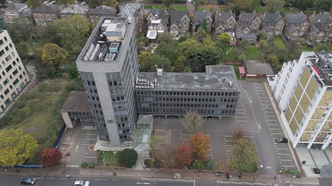 Orbital drone shot circling deteriorating modernist office complex showing architectural details in Ealing, London, October 2024