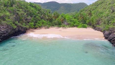 Beautiful-secret-tropical-sand-beach-surrounded-by-palm-trees,-aerial-forward