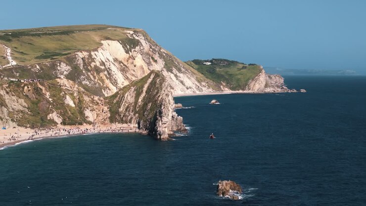 Giro a sinistra intorno a Durdle Door con scogliere e campi verdi sopra.