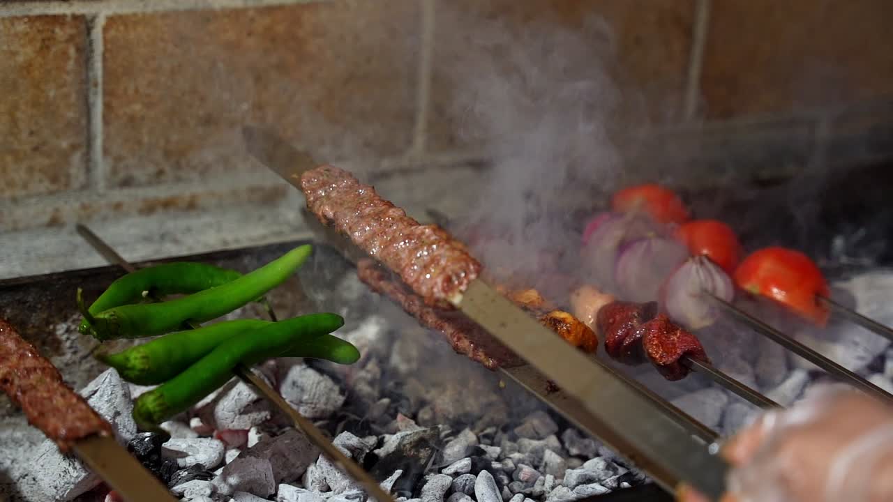 Primo piano di kebab sfrigolanti, verdure fresche e peperoncini verdi che cuociono su carboni ardenti, creando una scena barbecue affumicata e saporita con colori vivaci e un'atmosfera aromatica
