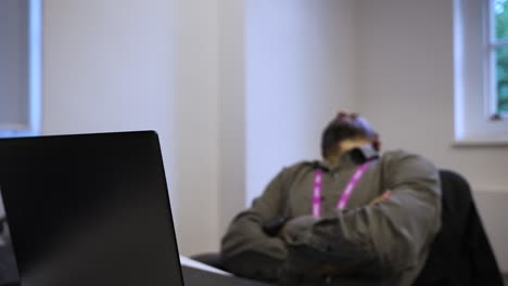 male office worker with arms crossed and head knelt back swivelling in chair