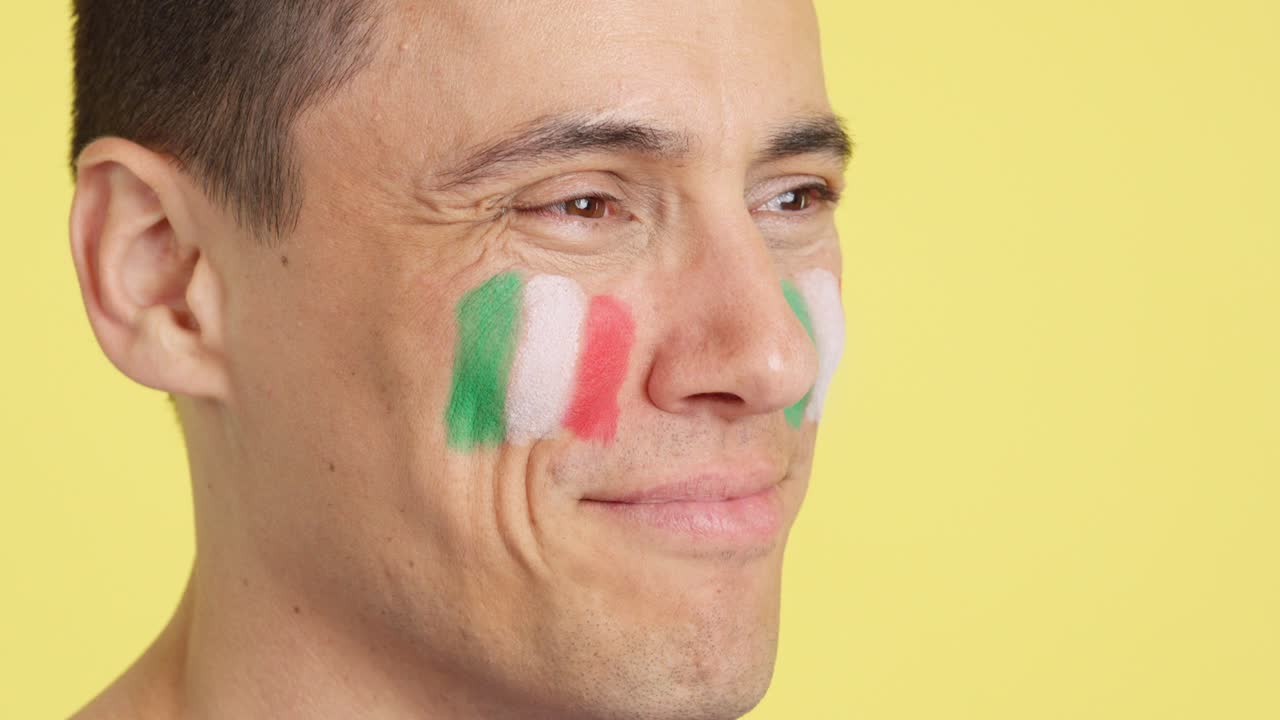 Happy man with spanish flag painted on face looking away