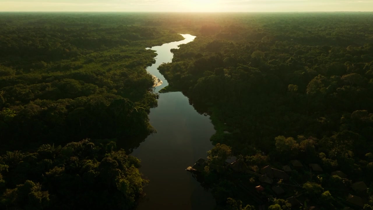 Majestætisk luftfoto over en snoet flod gennem den frodige Amazonas regnskov ved solnedgang.